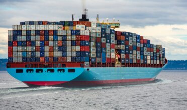 A heavily stocked cargo ship traverses ocean waters.